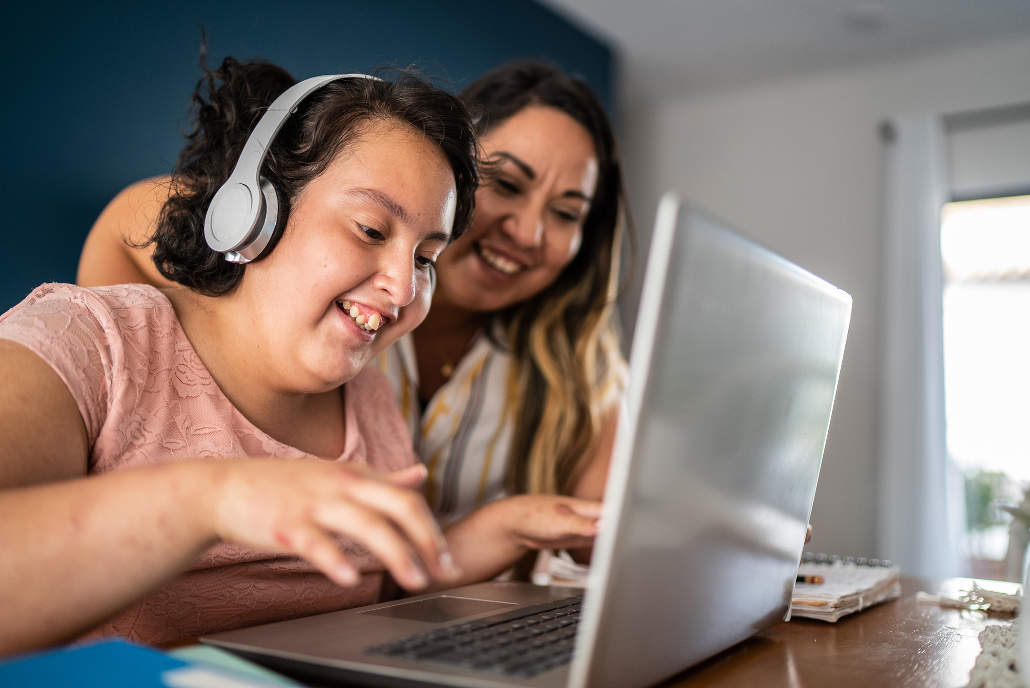 Mother helping psychomotor retardation girl using laptop studying at home